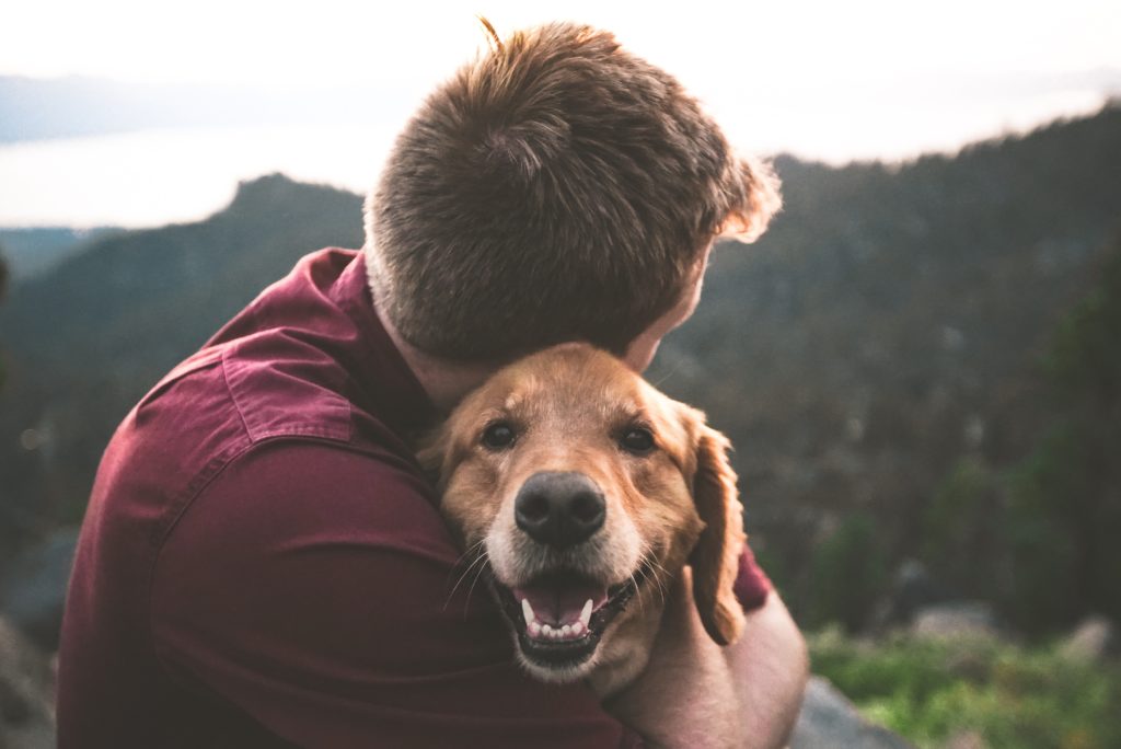 A man hugging his golden retriever dog ( mental health benefits of owning a dog)