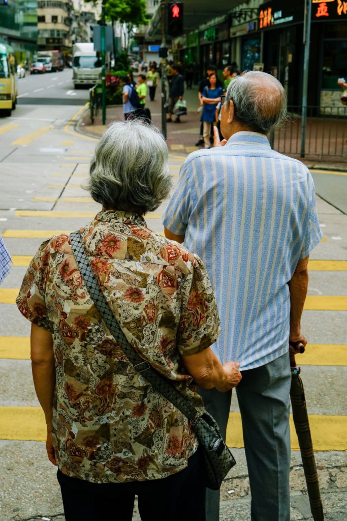 old couple roaming in the street back view 