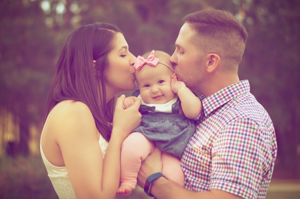 a young couple kissing baby's head ( peer pressure is a wrong reasons to have a baby)