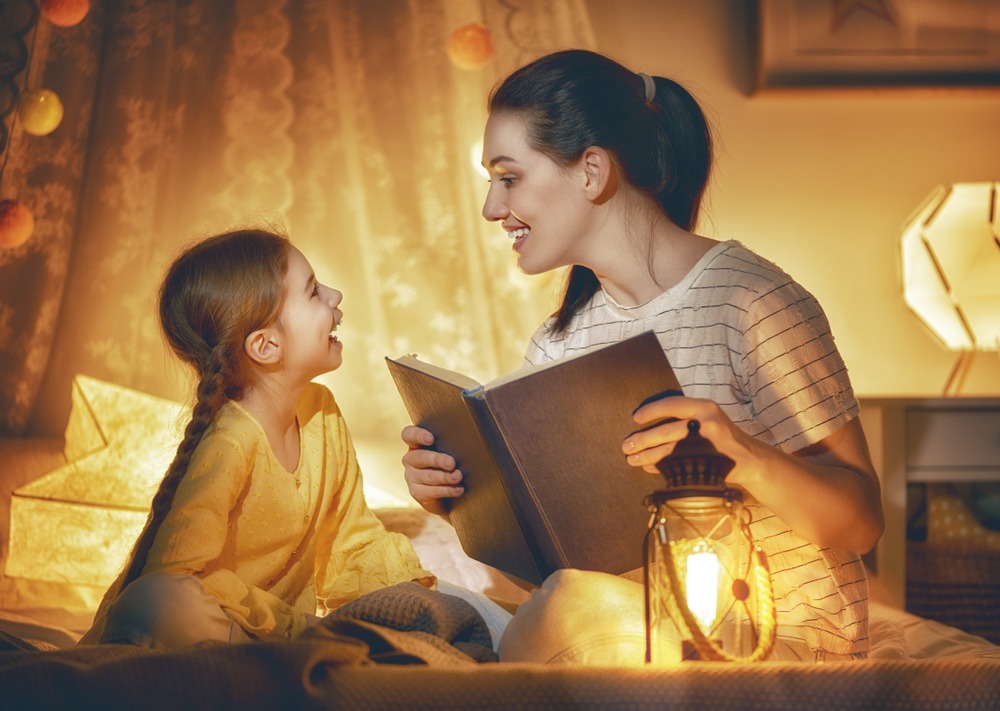 Mom telling story to daughter at bedtime ( a great activity to teach patience)