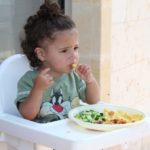 A fussy eater toddler eating his meal in high chair