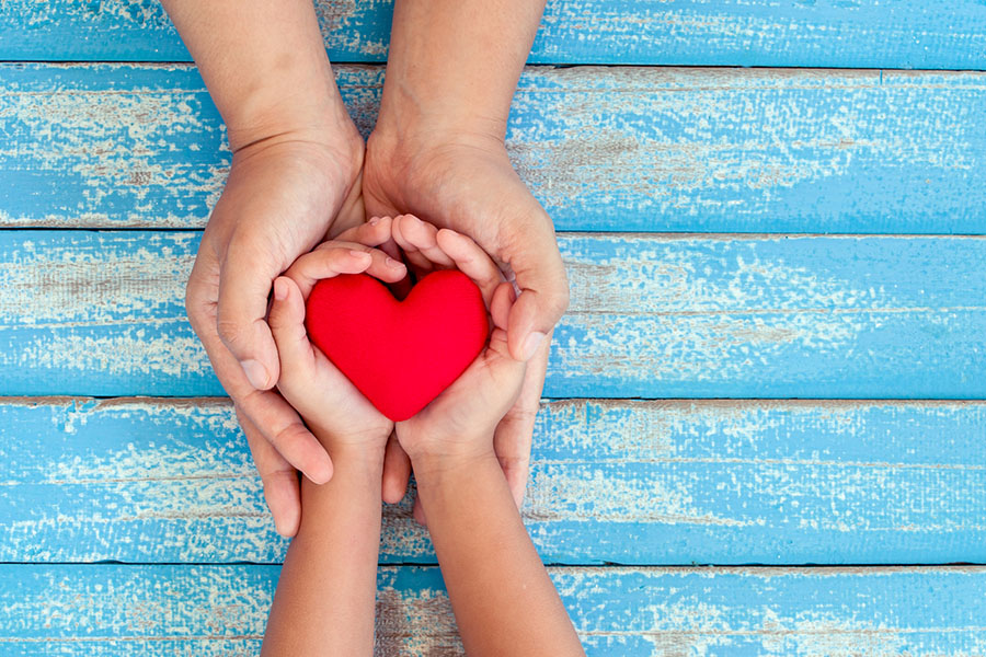 Mon holding child hands with a heart within (featured image positive parenting tips article)