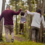 Parents in woods holding toddlers hands (Positive parenting tips for toddlers)